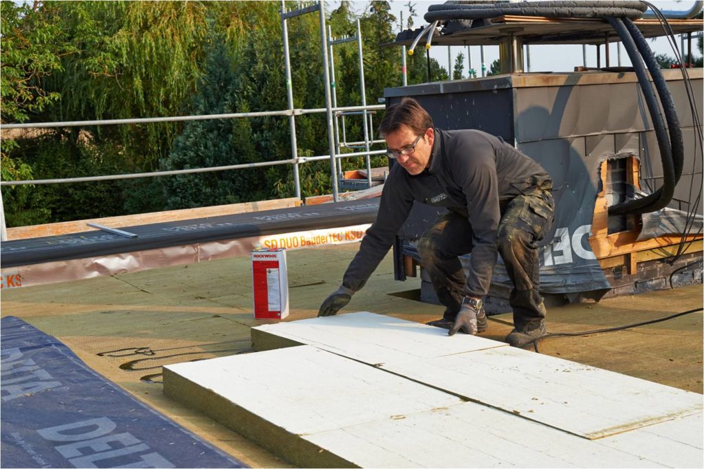 Im Hintergrund zu erkennen sind bereits die Anschlüsse für die Solarthermie. Die oberseitig mineralvlieskaschierten „Bondrock 040 MV“ Dämmstoffplatten sind besonders druckbelastbar. Deshalb konnten die Solarpaneele später ohne Bedenken auf der neuen Dämmung aufgestellt werden. (Copyright: Deutsche Rockwool GmbH & Co. KG)