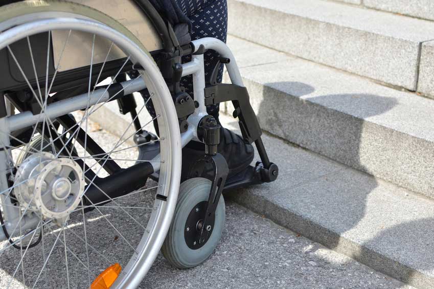 Gehbehinderte Frau im Rollstuhl von Stufen blockiert