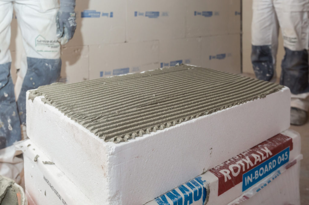 Vor der Wandmontage erhalten die Knauf Rotkalk in-Board Innendämmplatten ein ca. 5 mm dickflächiges Bett aus Knauf Rotkalk in-Klebemörtel, mit der Zahnspachtel aufgetragen. (Foto: Knauf/Stephan Klonk)