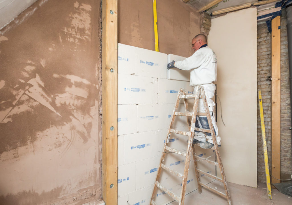 Auf die mit Rotkalk Grund egalisierte Wand wird das Innendämmsystem Knauf Rotkalk in-Board aus diffusionsoffenem Perlitgestein vollflächig verklebt. (Foto: Knauf/Stephan Klonk)